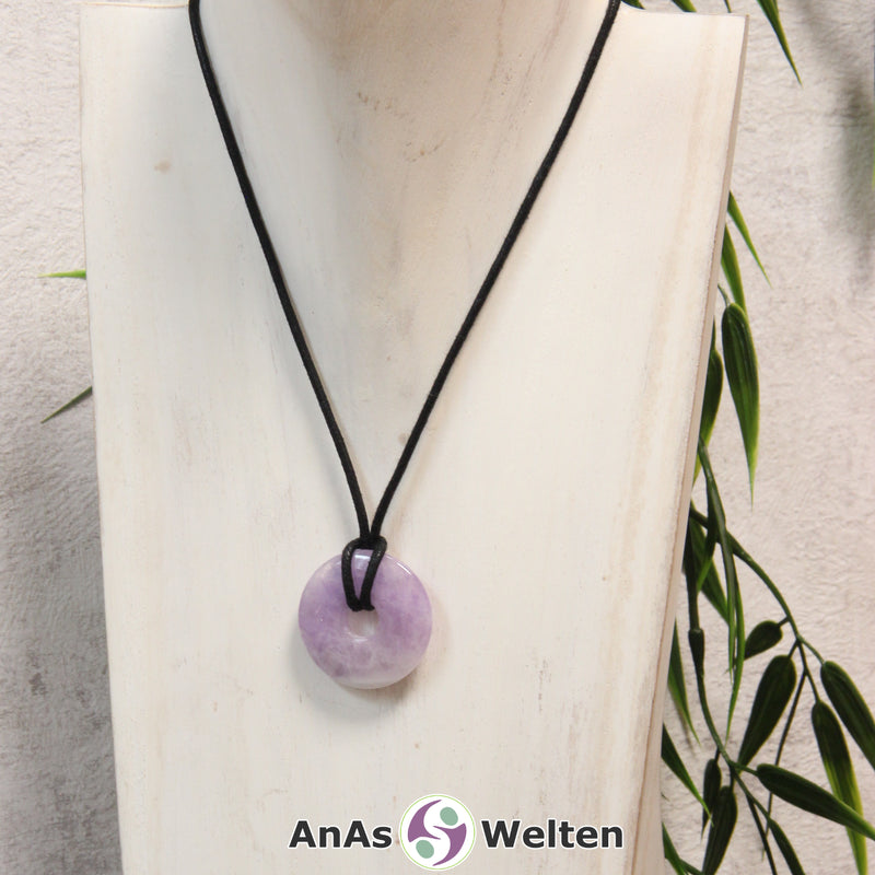 Ein Amethyst Donut als Kette an einem schwarzen gewachsten Baumwollband um eine helle Büste.