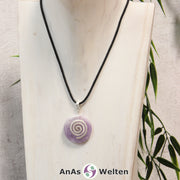 Ein Amethyst Donut an einem Donut-Halter Spirale, der mit einem gewachsten Baumwollband um eine helle Büste hängt.