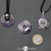 Drei Amethyst Donuts nebeneinander. Einer an einem Baumwollband, ein anderer an einem Donut-Halter mit Baumwollband.