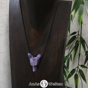 Ein Amethyst Wolf Anhänger an einem schwarzen Baumwollband, der um eine dunkle Büste gehängt wurde.