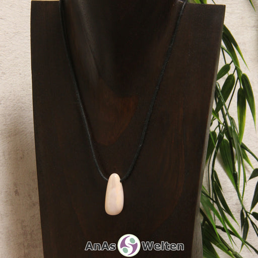Das Bild zeigt einen gebohrten Andenopal Trommelstein an einem Baumwollband. Der Andenopal ist rosa- bis beigefarben und hat eine zarte Musterung in einem etwas dunkleren Rosa-beige-Farbton.