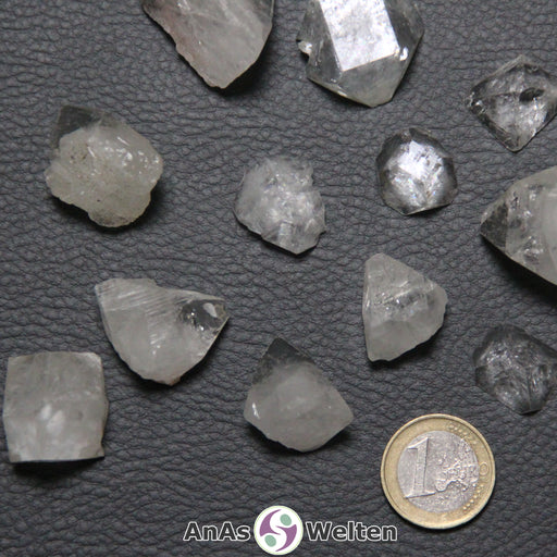 Das Bild zeigt den Apophyllit Kristall in verschiedenen Variationen. Er hat eine kantige Form und eine durchsichtige bis milchige Farbe.