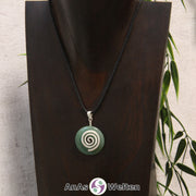 Ein Aventurin Donut an einem Donut-Halter Spirale, der mit einem gewachsten Baumwollband um eine dunkle Büste hängt.