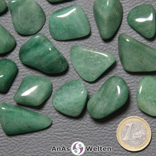 Das Produktbild zeigt mehrere Beispiele für einen Aventurin Trommelstein. Die Steine haben eine hell- bis dunkelgrüne Färbung. Mal sind sie relativ einfarbig, mal kann man deutlich unterschiedliche Schichten aus verschiedenen Grüntönen im Inneren erkennen.