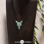 Ein Aventurin Wolf Anhänger an einem schwarzen Baumwollband, der um eine dunkle Büste gehängt wurde.