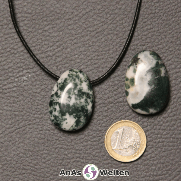 Zwei grün-weiße Moosachat gebohrte Trommelsteine nebeneinander. Einer befindet sich an einem schwarzen gewachsten Baumwollband.