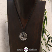 Das Produktbild zeigt einen Bergkristall Donut an einem Baumwollband. Der Edelsteindonut ist farblos, wodurch sich die eingeschlossenen Risse im Inneren in weiß abzeichnen.