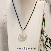 Ein Bergkristall Donut an einem Donut-Halter Spirale, der mit einem gewachsten Baumwollband um eine helle Büste hängt.