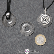 Drei Bergkristall Donuts nebeneinander. Einer an einem Baumwollband, ein anderer an einem Donut-Halter mit Baumwollband.