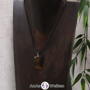 Ein Bernstein Anhänger Fische an einem Baumwollband als Kette um eine dunkle Büste.