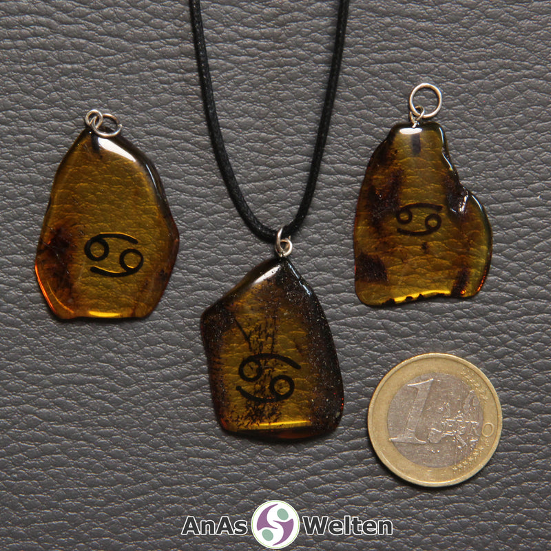 Drei Bernstein Anhänger Krebs in verschiedenen Formen. Das Sternzeichensymbol ist in die Bernsteine eingebrannt.