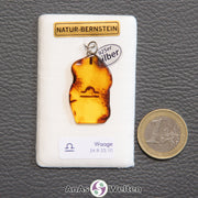 Ein Bernstein Anhänger Waage mit Silberöse an einem Display. Das Sternzeichen ist in den Bernstein eingebrannt.