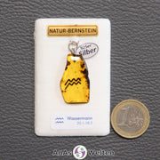 Ein Bernstein Anhänger Wassermann mit Silberöse an einem Display. Das Sternzeichen ist in den Bernstein eingebrannt.