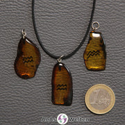 Drei Bernstein Anhänger Wassermann in verschiedenen Formen. Das Sternzeichensymbol ist in die Bernsteine eingebrannt.