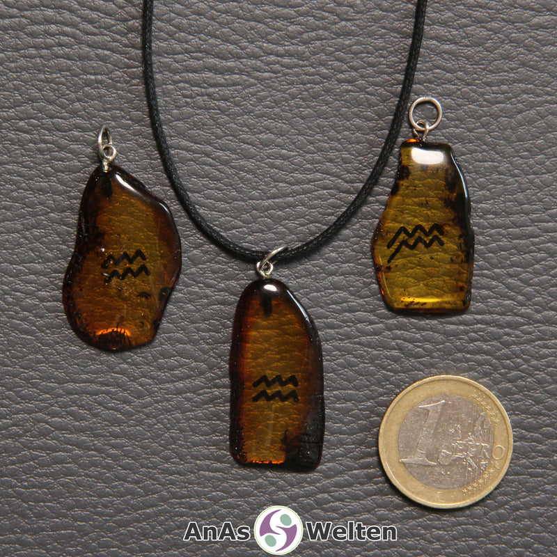 Drei Bernstein Anhänger Wassermann in verschiedenen Formen. Das Sternzeichensymbol ist in die Bernsteine eingebrannt.