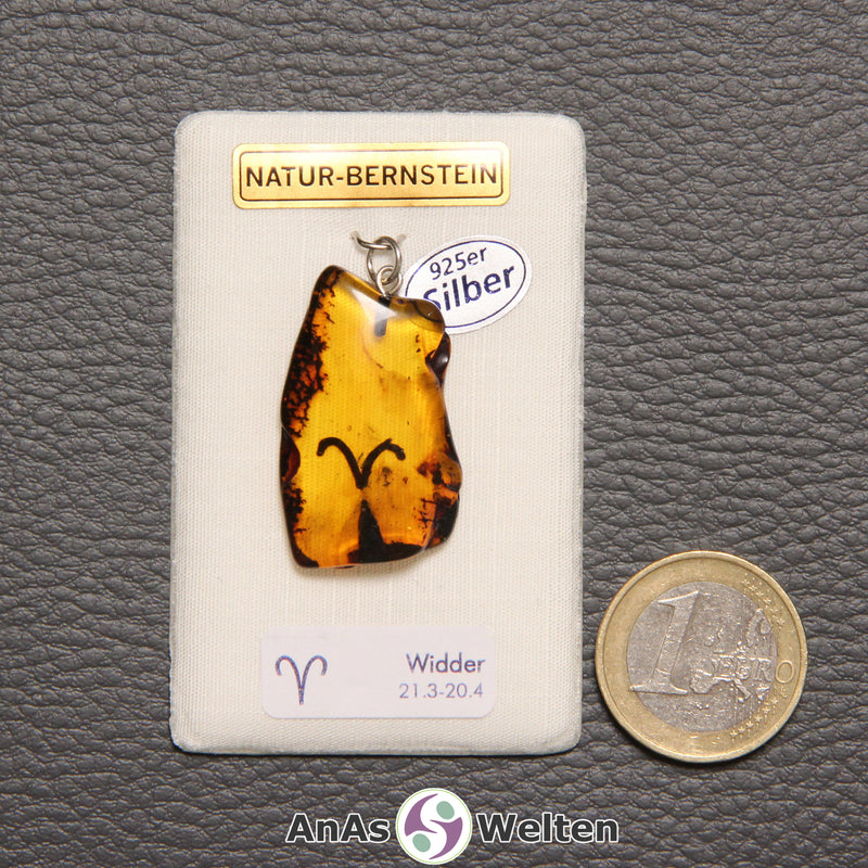 Ein Bernstein Anhänger Widder mit Silberöse an einem Display. Das Sternzeichen ist in den Bernstein eingebrannt.