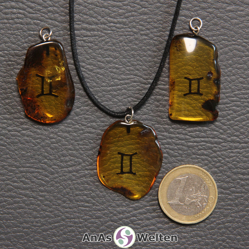 Drei Bernstein Anhänger Zwillinge in verschiedenen Formen. Das Sternzeichensymbol ist in die Bernsteine eingebrannt.