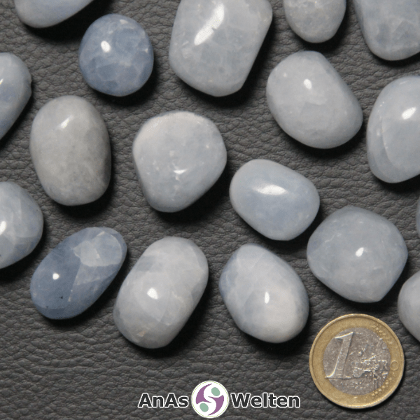 Auf dem Bild sind mehrere Beispiele für den blauer Calcit Trommelstein zu sehen. Der Edelstein hat eine hell- bis mittelblaue Farbe. Außerdem kann man helle Risse in seinem Inneren erkennen.