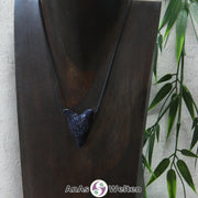 Ein Blaufluss Wolf Anhänger an einem schwarzen Baumwollband, der um eine dunkle Büste gehängt wurde.