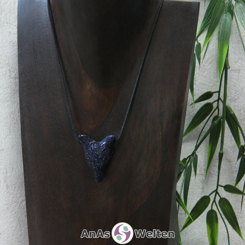 Ein Blaufluss Wolf Anhänger an einem schwarzen Baumwollband, der um eine dunkle Büste gehängt wurde.