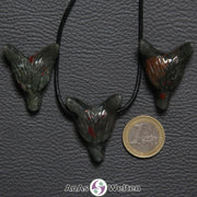 Drei Heliotrop Wolf Anhänger nebeneinander. Einer befindet sich an einem schwarzen Baumwollband.