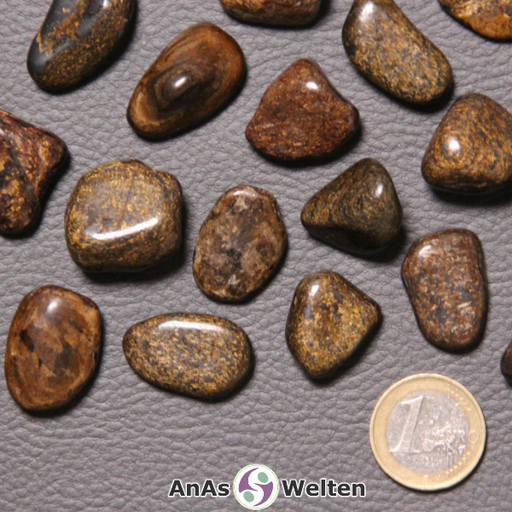 Das Bild zeigt den Bronzit Trommelstein in mehreren Beispielen. Besonders markant ist dabei die bronzene Farbe der Edelsteine, die von mehreren Brauntönen durchzogen ist.
