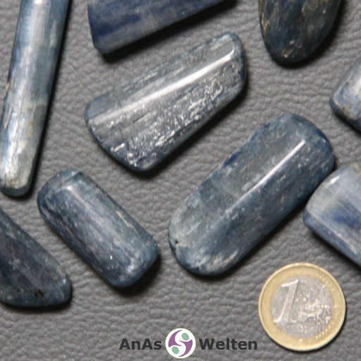 Das Produktbild zeigt einen Disthen Trommelstein in mehreren Beispielen. Die Edelsteine haben eine längliche Form. Außerdem haben sie eine dunkel-hellblaue Färbung und man kann ein silbriges Glitzern in ihrem Inneren erkennen.