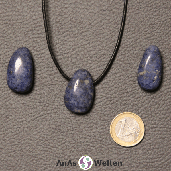 Drei blaue Dumortierit gebohrte Trommelsteine nebeneinander. Einer befindet sich an einem schwarzen gewachsten Baumwollband.