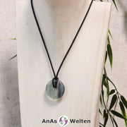 Ein Fluorit Donut als Kette an einem schwarzen gewachsten Baumwollband um eine helle Büste.