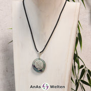 Ein Fluorit Donut an einem Donut-Halter Spirale, der mit einem gewachsten Baumwollband um eine helle Büste hängt.