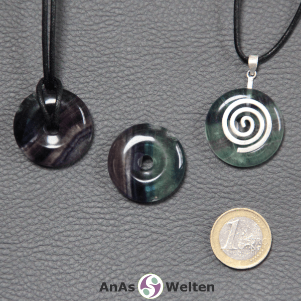 Drei Fluorit Donuts nebeneinander. Einer an einem Baumwollband, ein anderer an einem Donut-Halter mit Baumwollband.