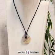 Ein Gelber Fluorit Donut als Kette an einem schwarzen gewachsten Baumwollband um eine helle Büste.