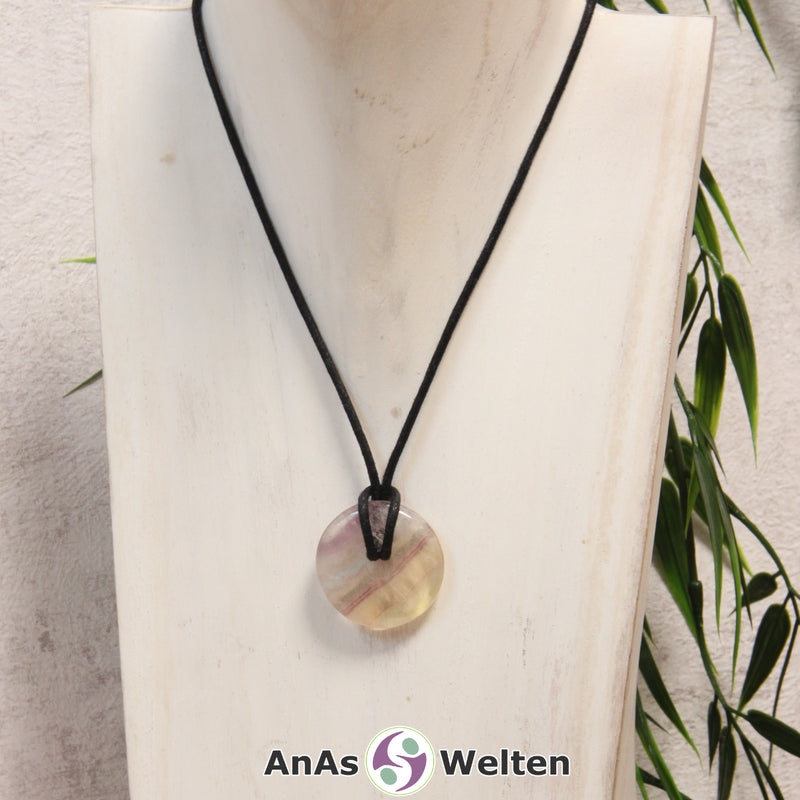 Ein Gelber Fluorit Donut als Kette an einem schwarzen gewachsten Baumwollband um eine helle Büste.