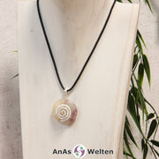 Ein Gelber Fluorit Donut an einem Donut-Halter Spirale, der mit einem gewachsten Baumwollband um eine helle Büste hängt.