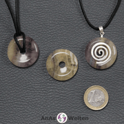 Drei Gelber Fluorit Donuts nebeneinander. Einer an einem Baumwollband, ein anderer an einem Donut-Halter mit Baumwollband.