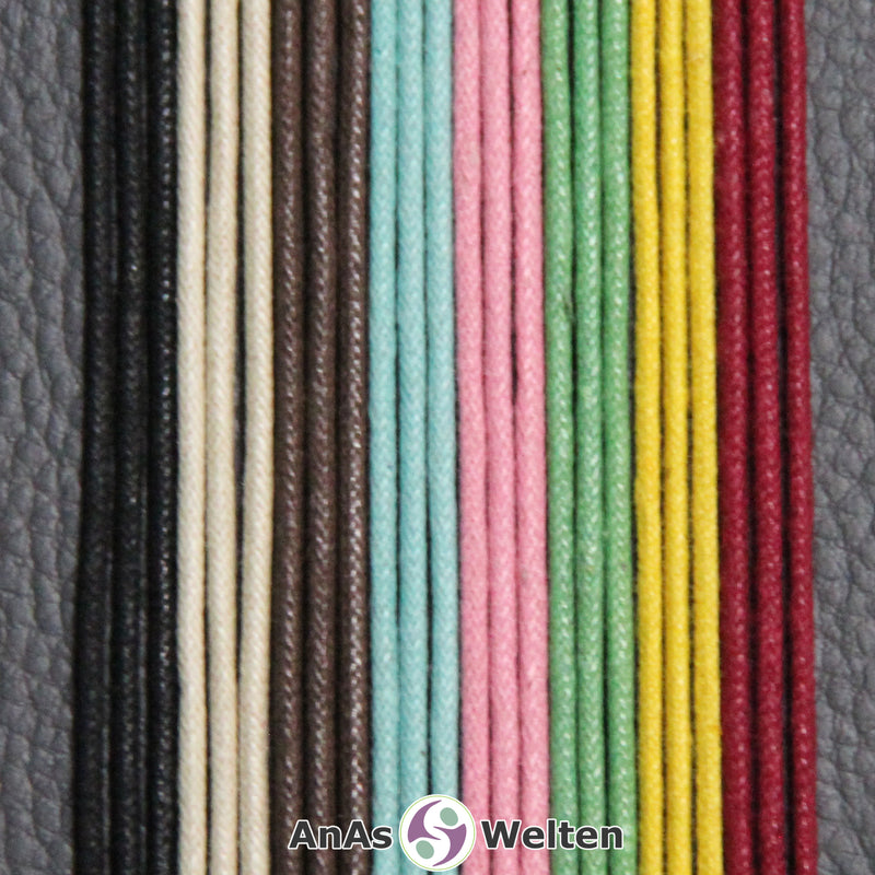 Das Bild zeigt ein gewachstes Baumwollband anhand dreier Beispiele in den jeweiligen Farben. Von links nach rechts sind das die Farben schwarz, beige, braun, türkis, rosa, grün, gelb und rot.