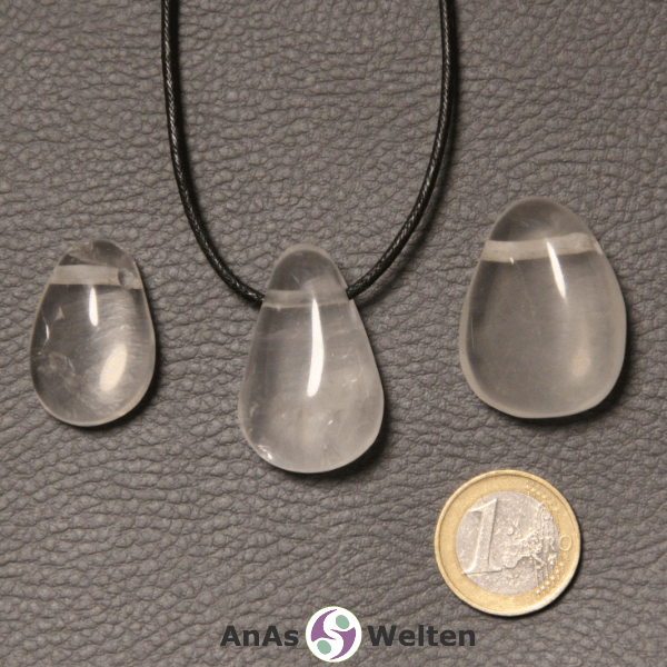 Drei durchsichtige Girasol gebohrte Trommelsteine nebeneinander. Einer befindet sich an einem schwarzen gewachsten Baumwollband.