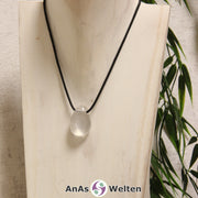 Ein dursichtiger Girasol gebohrter Trommelstein an einem schwarzen Baumwollband, der um eine helle Büste gehängt wurde.