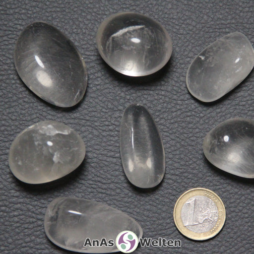 Das Bild zeigt einen Girasol Trommelstein anhand von mehreren Beispielsteinen. Die Edelsteine sind durchsichtig und haben gelegentlich eine leicht milchige Färbung. Außerdem kann man in einigen von ihnen Einschlüsse und weiße Risse erkennen.