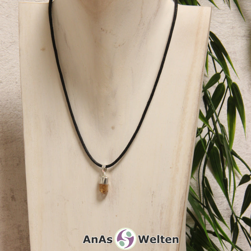 Ein gelber Goldtopas Stein mit Öse an einem schwarzen Baumwollband, der um eine helle Büste gehängt wurde.