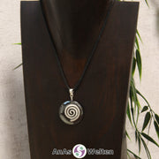 Ein Hämatit Donut an einem Donut-Halter Spirale, der mit einem gewachsten Baumwollband um eine dunkle Büste hängt.