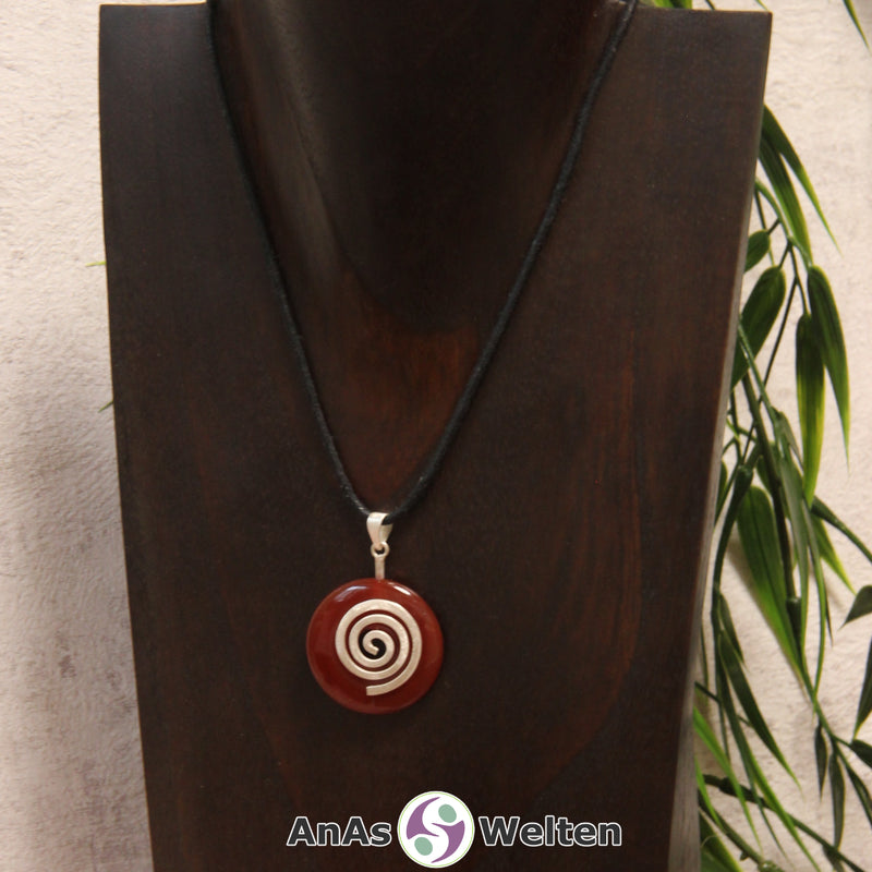 Ein Karneol Donut an einem Donut-Halter Spirale, der mit einem gewachsten Baumwollband um eine dunkle Büste hängt.