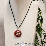 Ein Karneol Donut an einem Donut-Halter Spirale, der mit einem gewachsten Baumwollband um eine helle Büste hängt.