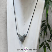 Ein Labradorit Wolf Anhänger an einem schwarzen Baumwollband, der um eine dunkle Büste gehängt wurde.