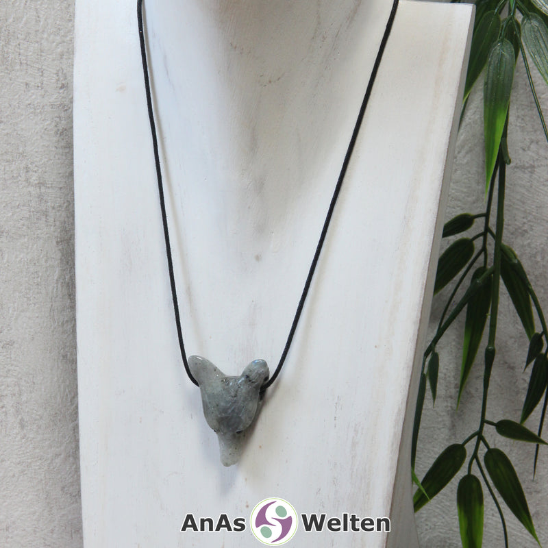 Ein Labradorit Wolf Anhänger an einem schwarzen Baumwollband, der um eine dunkle Büste gehängt wurde.