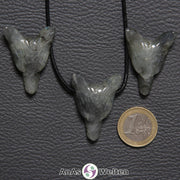 Drei Labradorit Wolf Anhänger nebeneinander. Einer befindet sich an einem schwarzen Baumwollband.