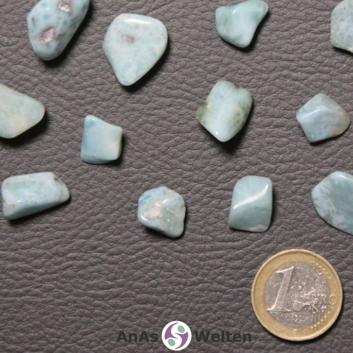 Das Bild zeigt einen Larimar Trommelstein anhand von mehreren Beispielsteinen. Die Edelsteine haben eine zarte hellblaue Farbe mit gelegentlichen weißen und grauen Einschlüssen.