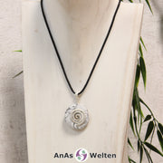 Ein Magnesit Donut an einem Donut-Halter Spirale, der mit einem gewachsten Baumwollband um eine helle Büste hängt.