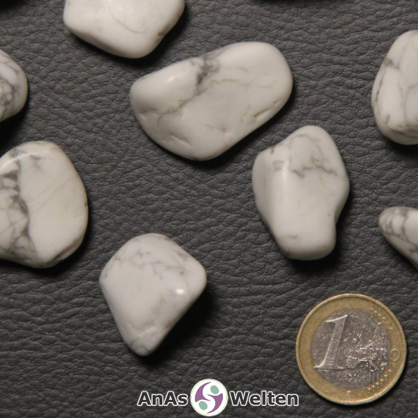 Das Produktbild zeigt einen Magnesit Trommelstein als mehrere Beispielsteine. Die Edelsteine haben Marmoroptik. Sie sind weiß und weisen die typischen grauen Linien auf.