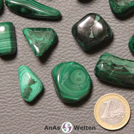 Das Bild zeigt einen Malachit Trommelstein anhand mehrerer Beispielsteine. Die Edelsteine haben alle mehrere Grüntöne mit unterschiedlichsten Musterungen. Viele sind in verschiedenen Grüntönen gestreift.